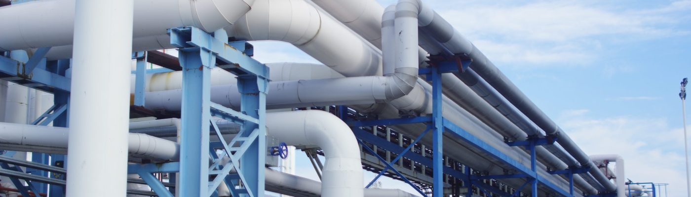 A closeup of industrial pipelines around a factor on a sunny day