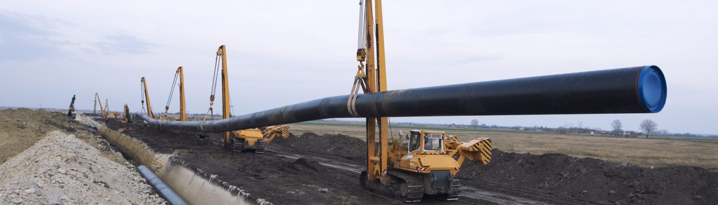 Heavy duty construction machines carrying and placing gas pipe into the ground.
